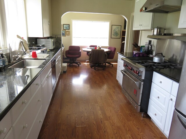 kitchen with white cabinetry, dark hardwood / wood-style flooring, wall chimney range hood, and luxury stove