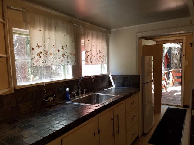 kitchen featuring white fridge, sink, tile countertops, and backsplash