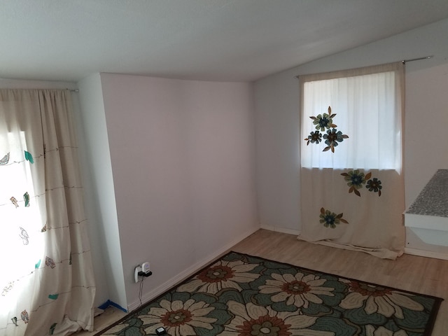 unfurnished room featuring vaulted ceiling and wood-type flooring