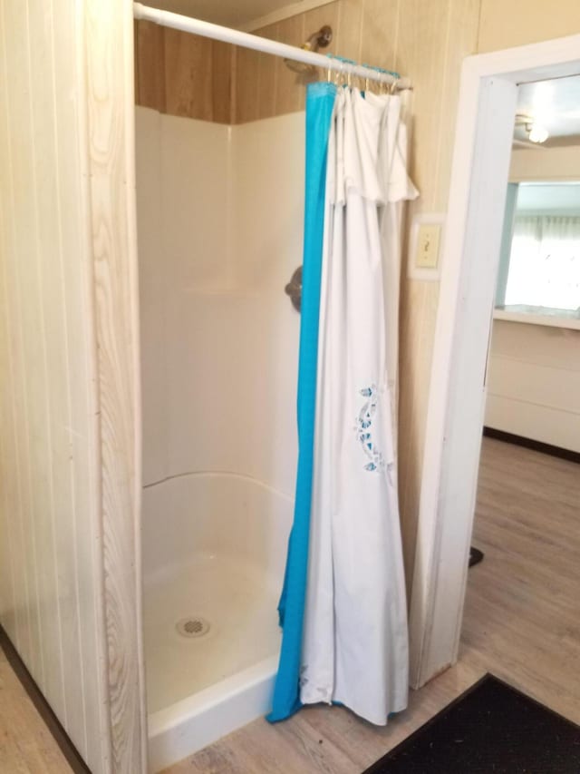 bathroom with hardwood / wood-style flooring and walk in shower