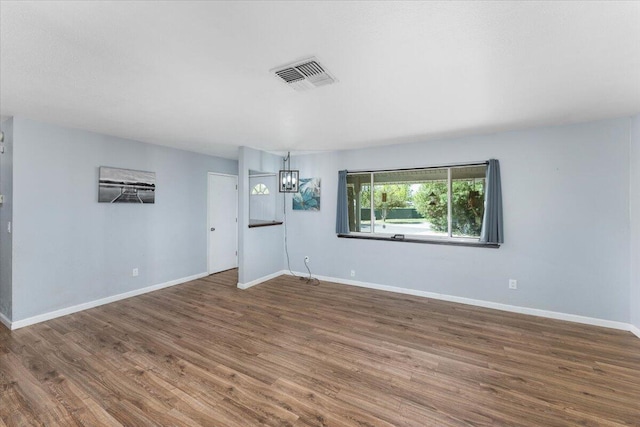 empty room with hardwood / wood-style floors and a notable chandelier