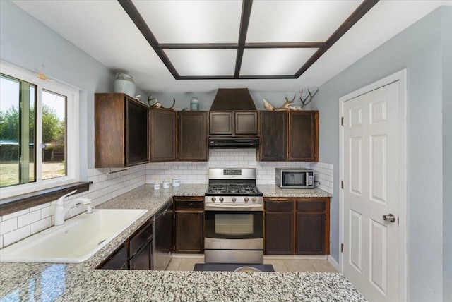 kitchen featuring light stone counters, stainless steel appliances, sink, and decorative backsplash