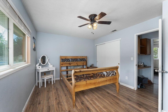 bedroom featuring ceiling fan, dark hardwood / wood-style floors, a closet, and multiple windows