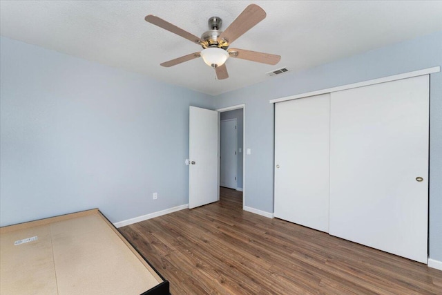 unfurnished bedroom featuring dark wood-type flooring, ceiling fan, and a closet