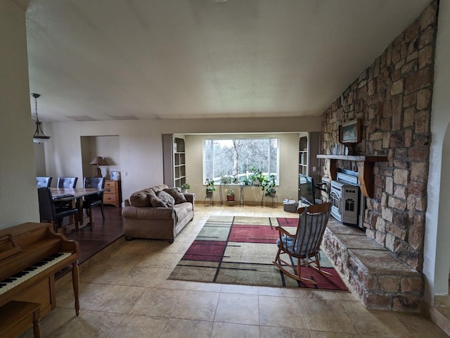 living room featuring vaulted ceiling and a stone fireplace