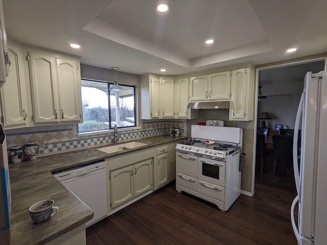 kitchen with white appliances, a tray ceiling, dark hardwood / wood-style flooring, white cabinets, and sink