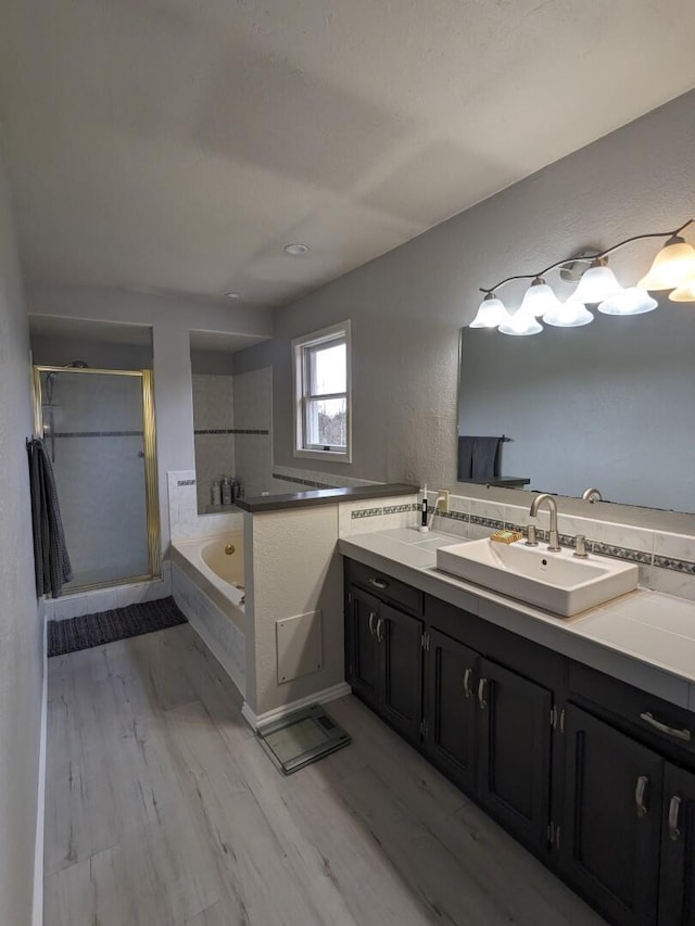 bathroom with hardwood / wood-style flooring, vanity, and shower with separate bathtub