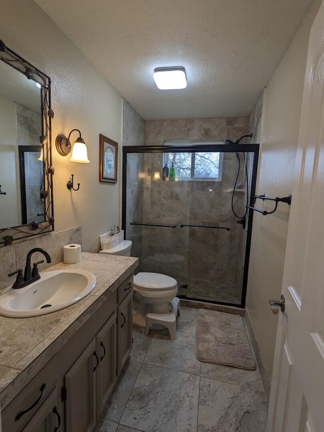 bathroom with a textured ceiling, an enclosed shower, vanity, and toilet