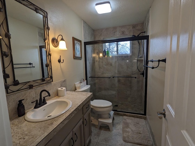 bathroom featuring toilet, a shower with door, vanity, and decorative backsplash