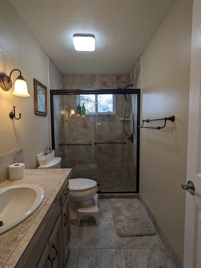 bathroom with toilet, an enclosed shower, vanity, and a textured ceiling