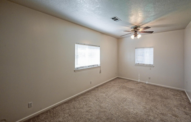 empty room with ceiling fan, carpet floors, and a textured ceiling