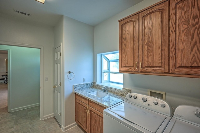 washroom with washing machine and dryer, sink, light tile patterned flooring, and cabinets