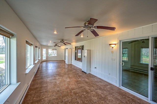 unfurnished sunroom featuring baseboard heating and ceiling fan