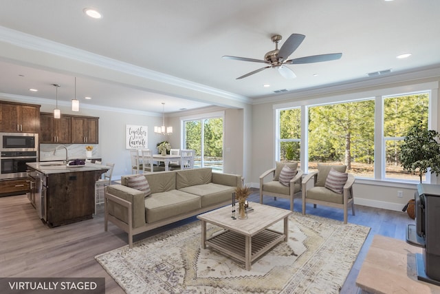 living room featuring light hardwood / wood-style floors, crown molding, sink, and plenty of natural light