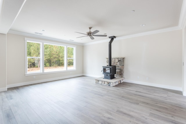 unfurnished living room with crown molding, light hardwood / wood-style floors, and a wood stove