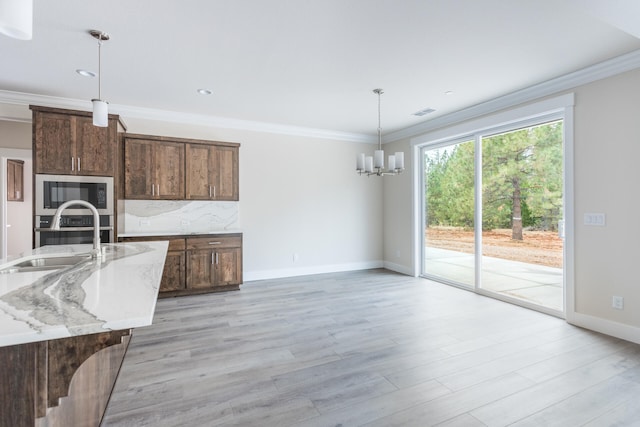 kitchen with light stone counters, appliances with stainless steel finishes, light hardwood / wood-style flooring, crown molding, and decorative light fixtures