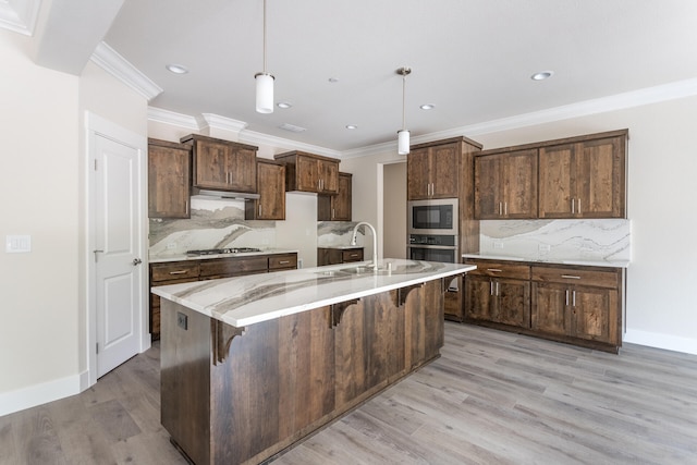 kitchen with stainless steel appliances, backsplash, sink, decorative light fixtures, and light wood-type flooring