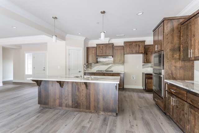 kitchen featuring decorative backsplash, light hardwood / wood-style flooring, stainless steel appliances, pendant lighting, and sink