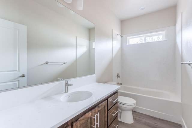 full bathroom with toilet, hardwood / wood-style flooring, vanity, and washtub / shower combination