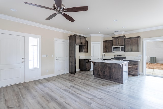 kitchen featuring light hardwood / wood-style floors, stainless steel appliances, crown molding, and a kitchen island with sink