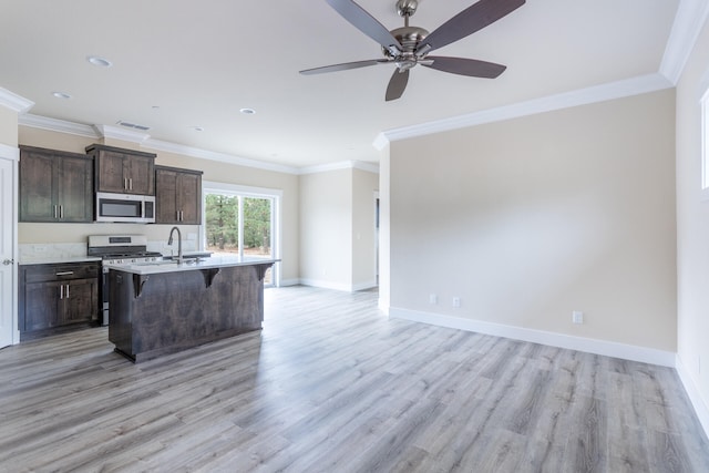 kitchen featuring a center island with sink, a breakfast bar, light hardwood / wood-style floors, crown molding, and stainless steel appliances