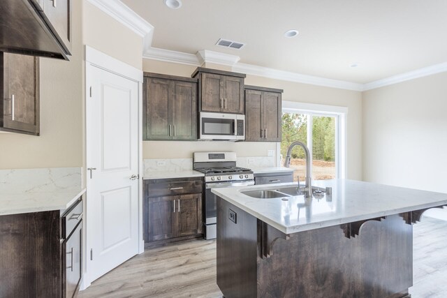 kitchen with appliances with stainless steel finishes, a kitchen island with sink, and light wood-type flooring