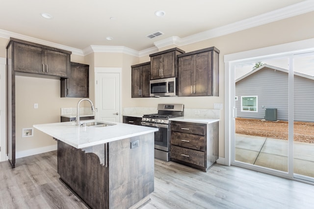 kitchen with a center island with sink, sink, light hardwood / wood-style floors, crown molding, and stainless steel appliances