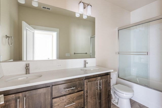 full bathroom with toilet, enclosed tub / shower combo, vanity, and hardwood / wood-style floors