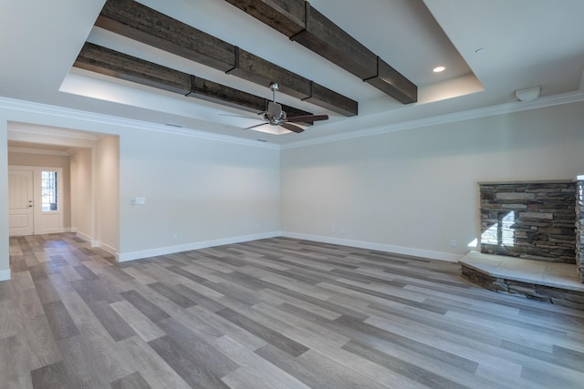 unfurnished living room with ceiling fan, beam ceiling, hardwood / wood-style flooring, and a tray ceiling