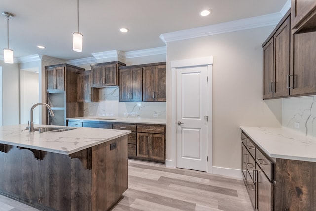 kitchen with light wood-type flooring, decorative light fixtures, backsplash, and light stone countertops