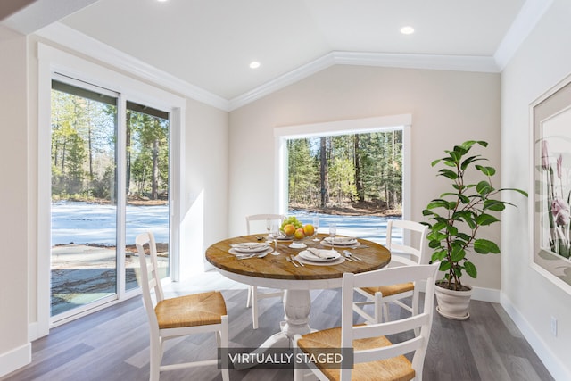 dining room featuring hardwood / wood-style floors, a wealth of natural light, vaulted ceiling, and ornamental molding