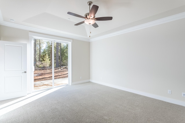 unfurnished room featuring a tray ceiling, ceiling fan, ornamental molding, and carpet