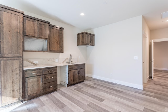 kitchen with sink, dark brown cabinetry, and light hardwood / wood-style flooring