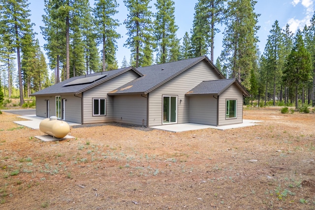 back of house with a patio area and solar panels