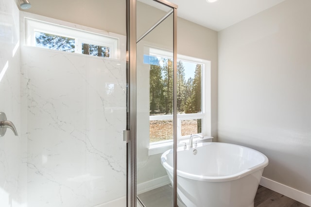 bathroom with hardwood / wood-style flooring, plenty of natural light, and separate shower and tub