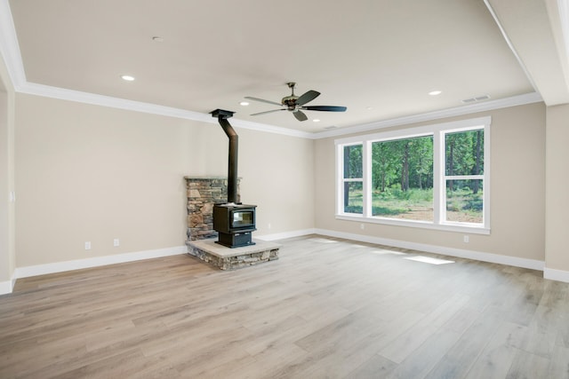 unfurnished living room featuring a wood stove, crown molding, light hardwood / wood-style flooring, and ceiling fan