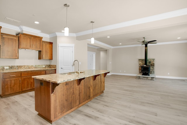 kitchen featuring sink, an island with sink, decorative light fixtures, and light hardwood / wood-style flooring