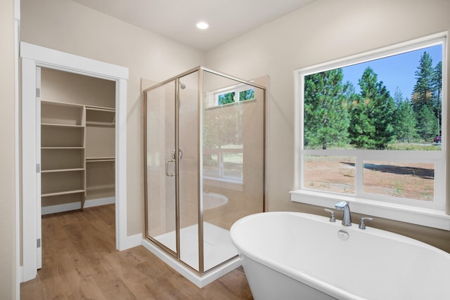 bathroom featuring plus walk in shower, hardwood / wood-style floors, and a wealth of natural light