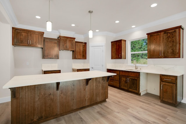 kitchen with hanging light fixtures, a kitchen island, ornamental molding, light hardwood / wood-style floors, and sink