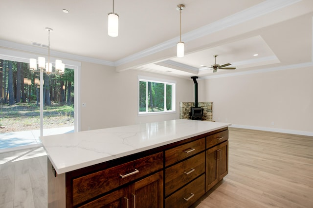 kitchen with light hardwood / wood-style floors, a wood stove, hanging light fixtures, and crown molding