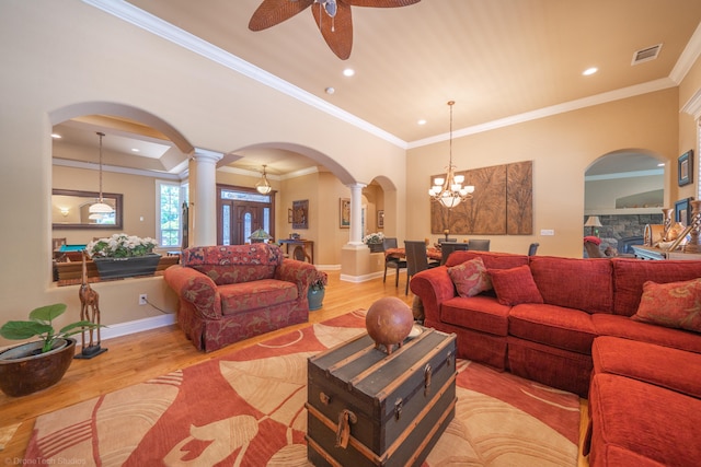 living room featuring ornate columns, ceiling fan with notable chandelier, light hardwood / wood-style floors, and ornamental molding