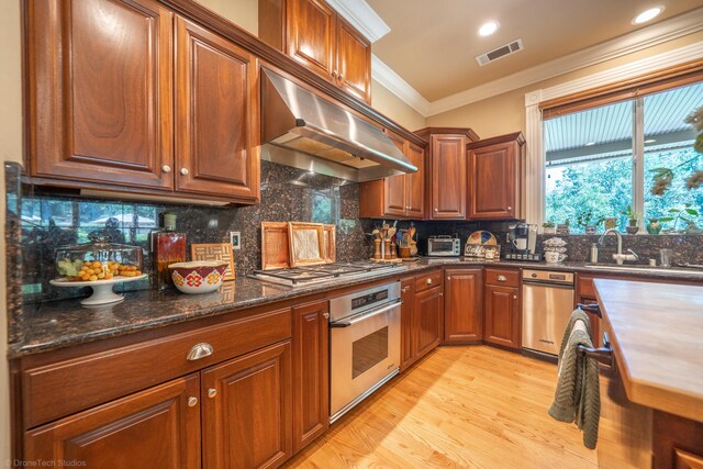 kitchen with dark stone counters, light hardwood / wood-style flooring, backsplash, ornamental molding, and stainless steel appliances