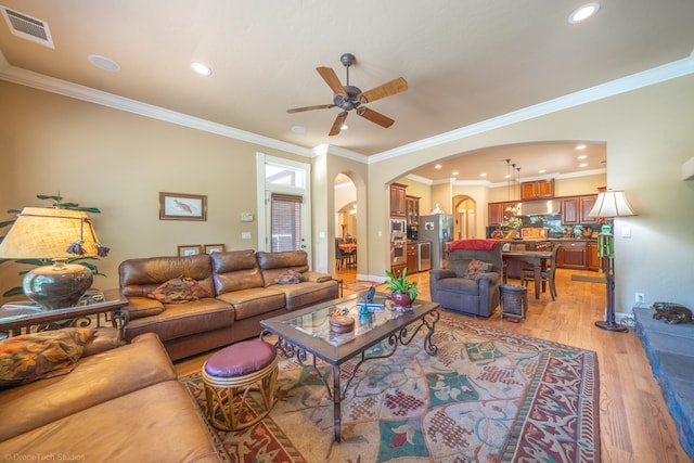 living room with light hardwood / wood-style floors, crown molding, and ceiling fan