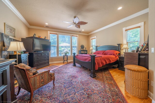 bedroom featuring ceiling fan, multiple windows, and ornamental molding