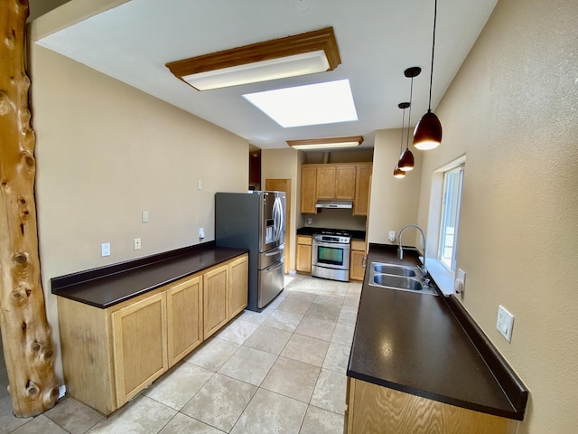 kitchen with a skylight, a sink, under cabinet range hood, appliances with stainless steel finishes, and dark countertops