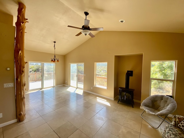 unfurnished living room with light tile patterned flooring, baseboards, a wood stove, and a ceiling fan