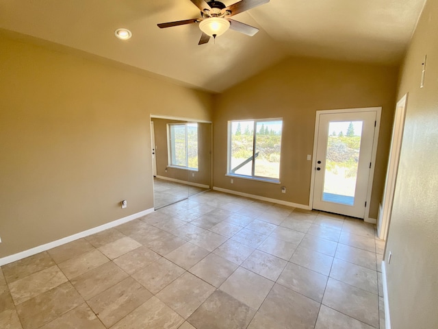 empty room with vaulted ceiling, light tile patterned flooring, a ceiling fan, and baseboards