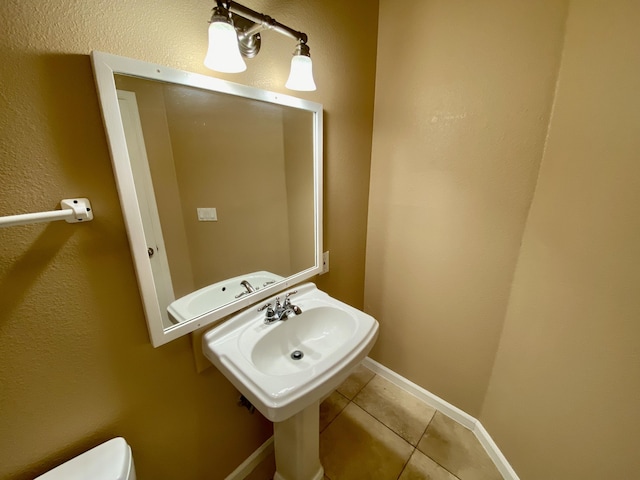 bathroom with tile patterned floors, toilet, baseboards, and a sink