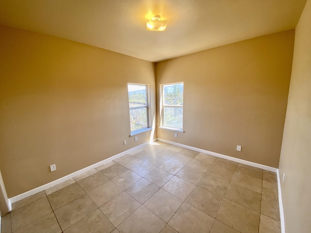 empty room featuring light tile patterned flooring and baseboards