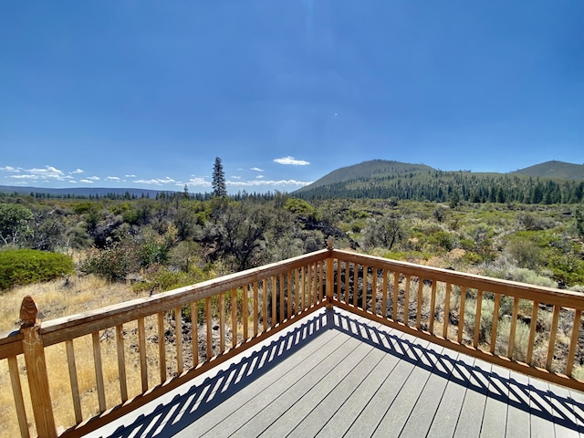 deck featuring a mountain view and a view of trees